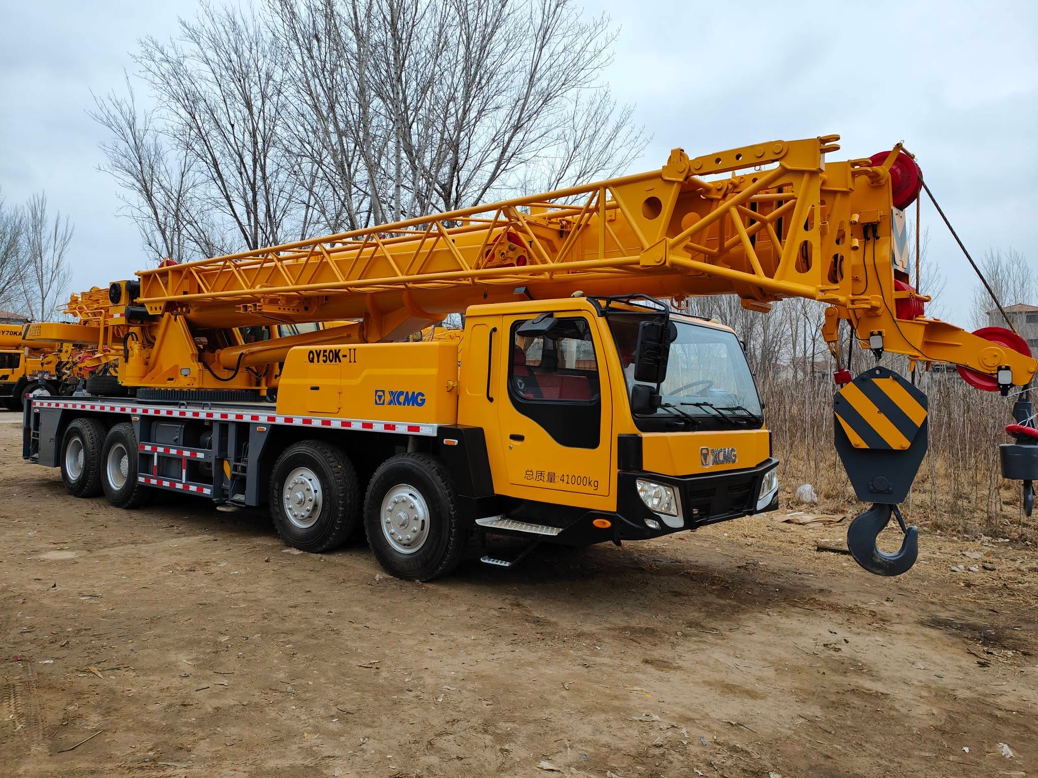 XCMG truck crane with yellow and black color scheme, standing on construction site with clear sky background, professional industrial equipment photography
