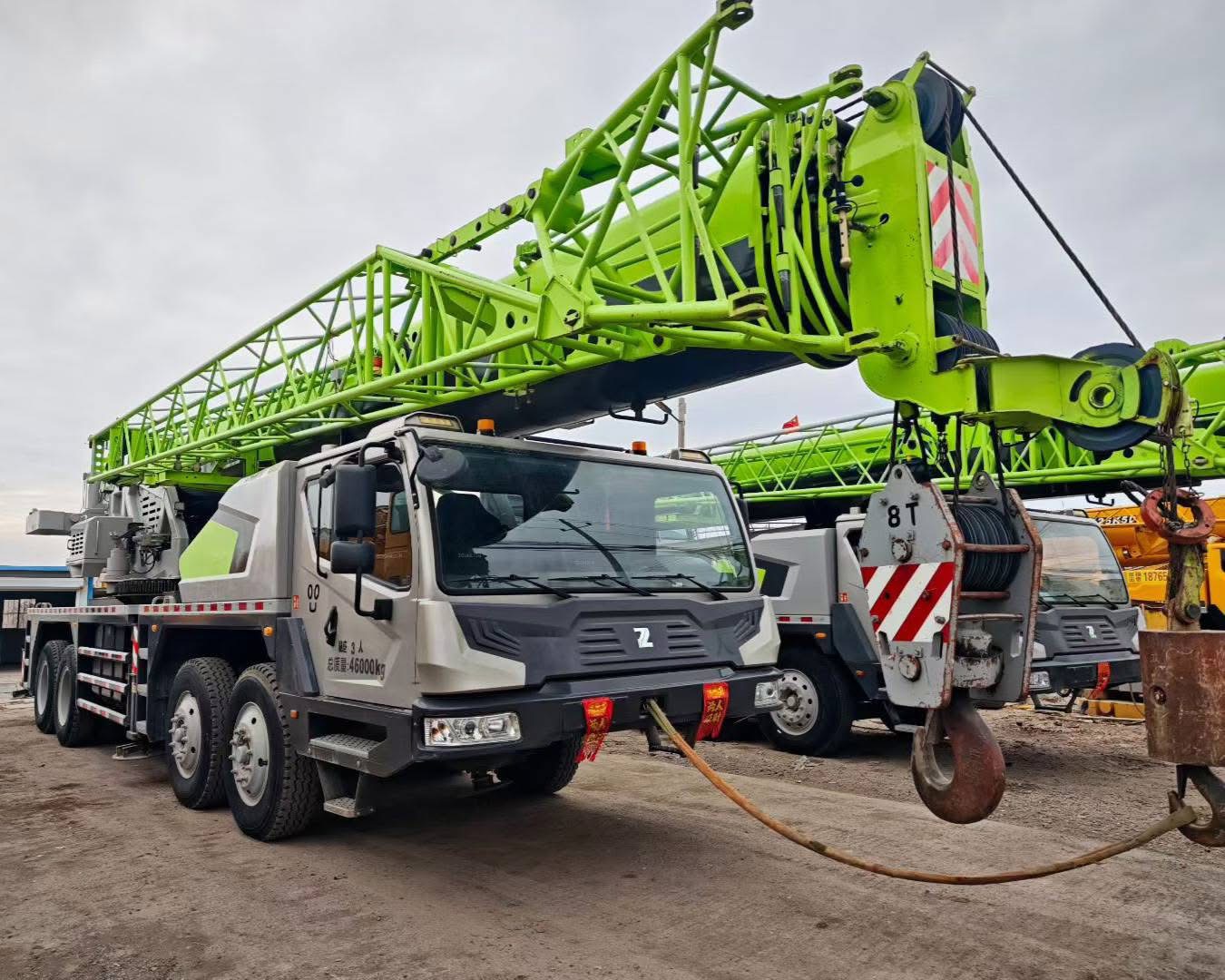 Zoomlion truck crane with red and white color scheme, positioned on road with urban background, professional construction equipment photography