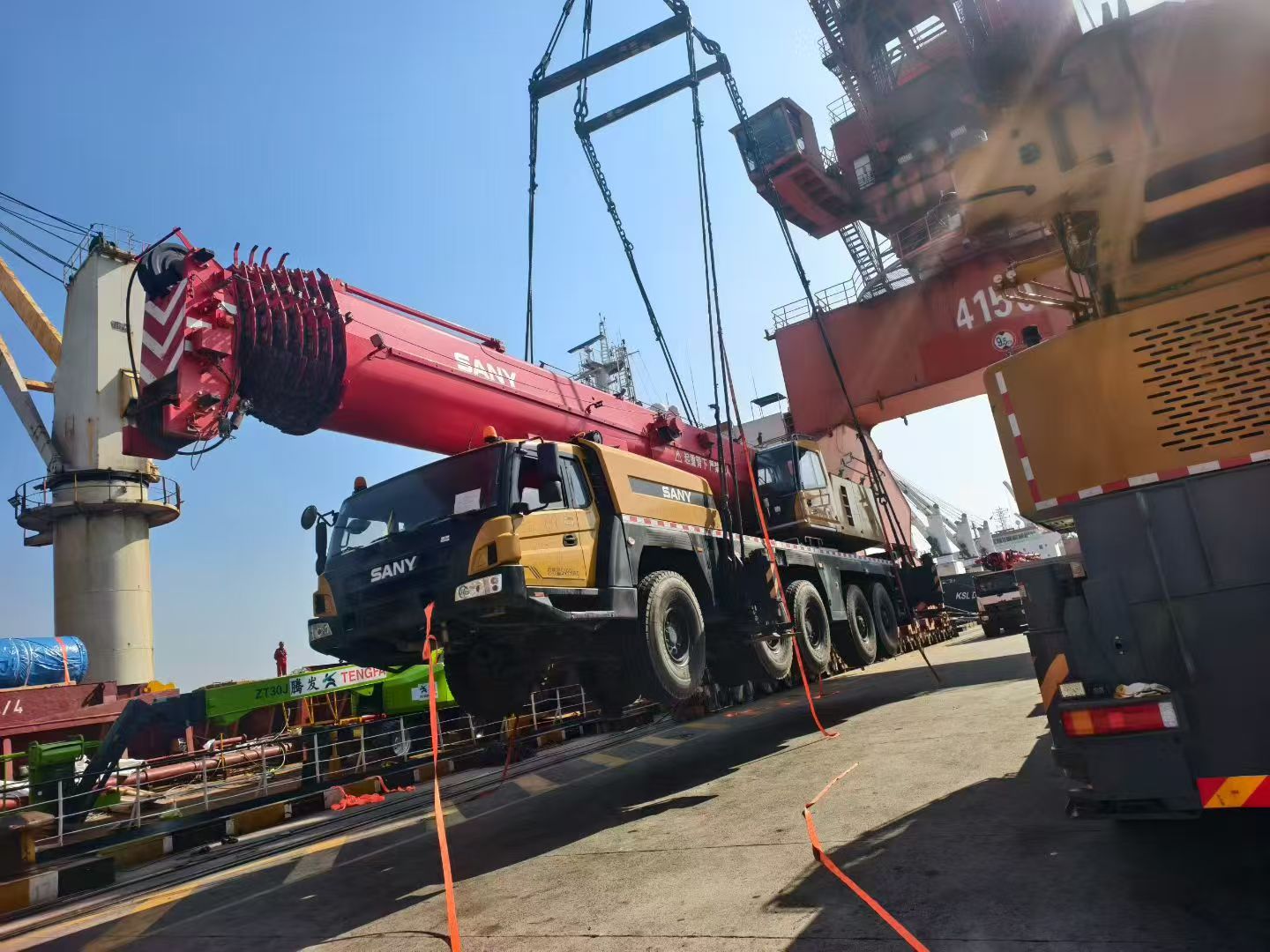 Construction equipment yard with various cranes and machinery, organized storage area, outdoor industrial environment